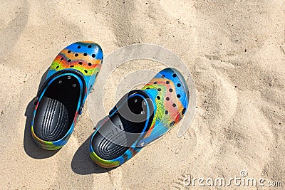 Colorful crocs footwear on the beach, vacation background. Colorful trendy croc beach shoes. Editorial Stock Photo